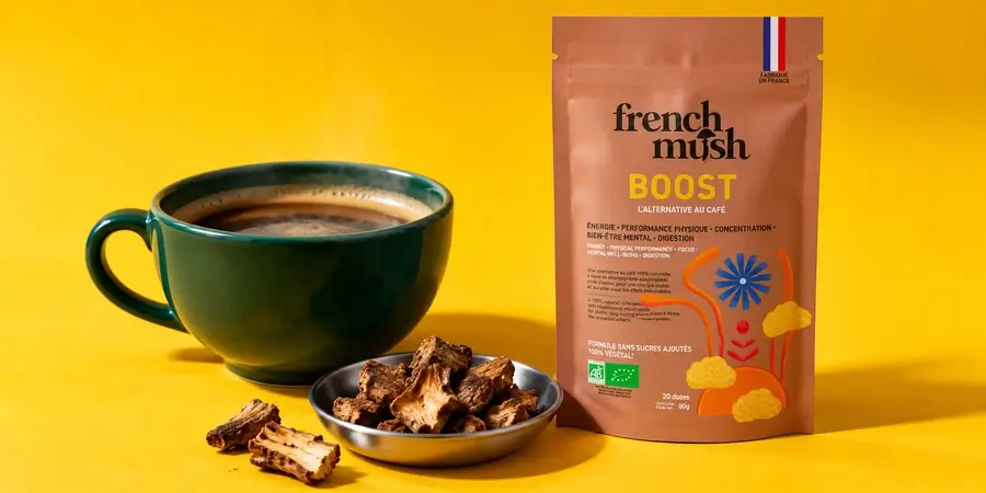 Busta di French Mush Boost Cicoria con una tazza di bevanda alla cicoria e pezzi di radice di cicoria tostata su fondo giallo