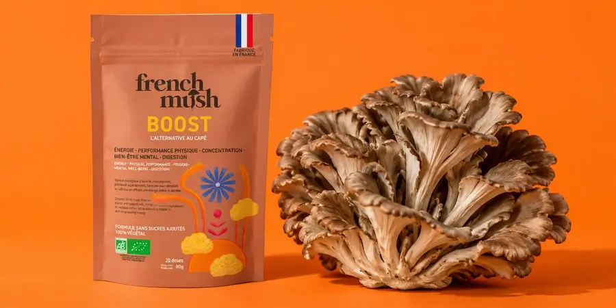Busta di French Mush Boost Cicoria accanto a un cespo di maitake fresco su fondo arancione acceso